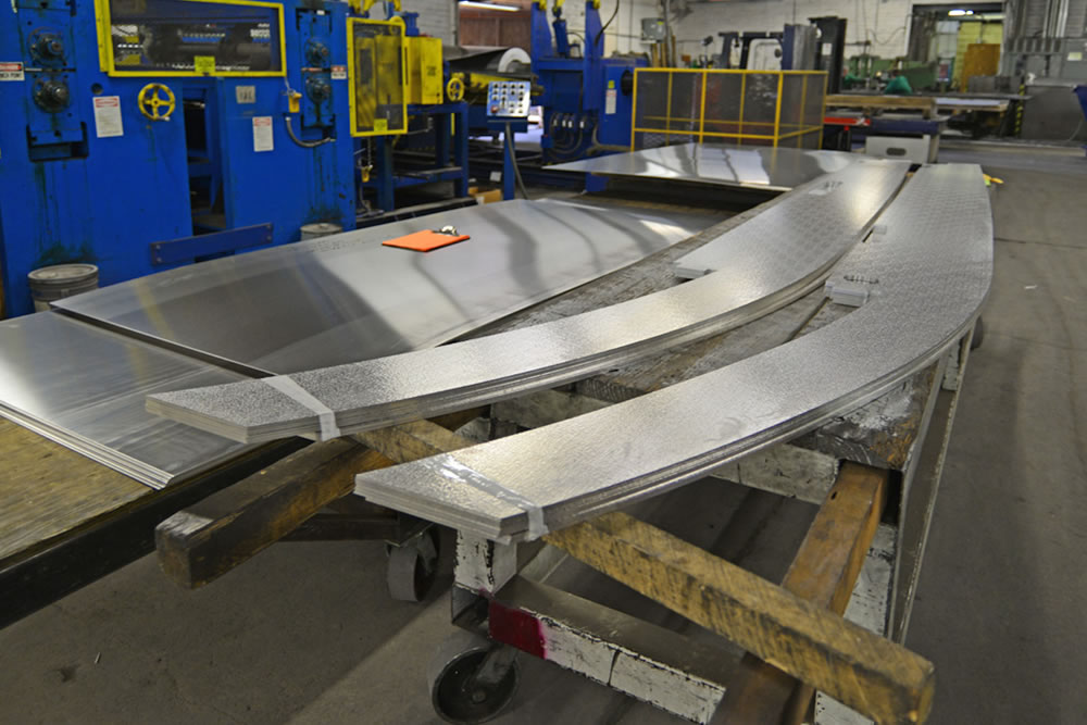 A CNC cutter chops flat aluminum sheets into various parts.